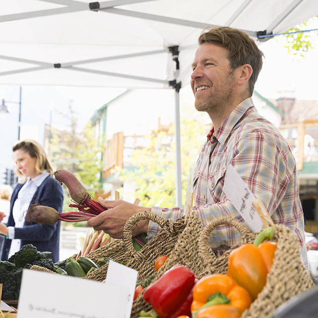 Người đàn ông thanh toán tiền rau ngoài trời bằng thiết bị di động