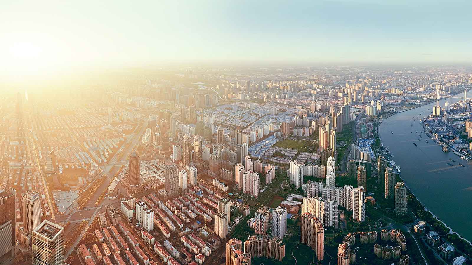 Bird's eye view of a city beside a river in the early morning light.