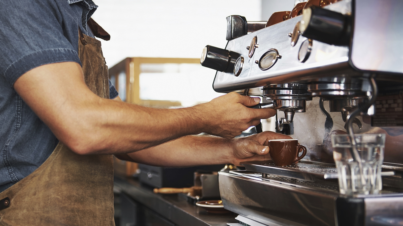 A barista preparing an espresso drink in a coffee shop.
