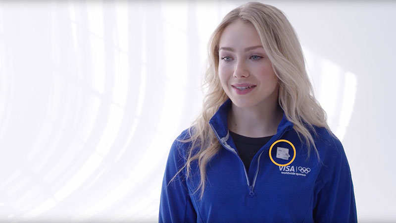 Freestyle skier Maggie Voison poses in front of a white background displaying wearable payment.