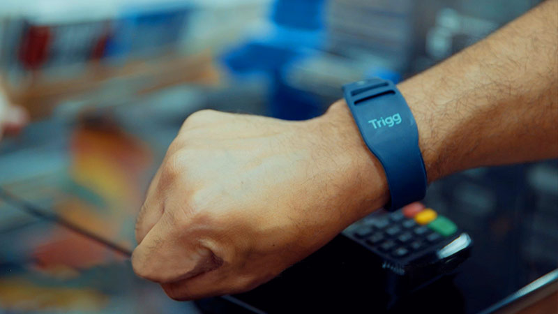 Close up of a person using a watch to pay, with the Trigg logo on the watch.