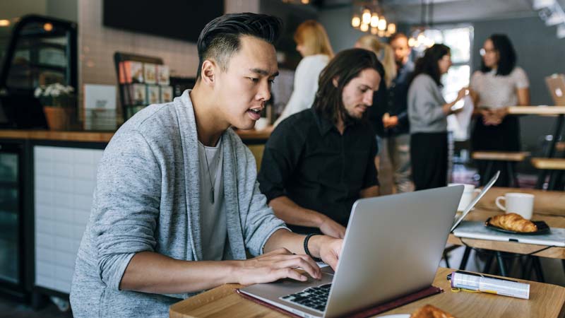 Men using laptops in cafe