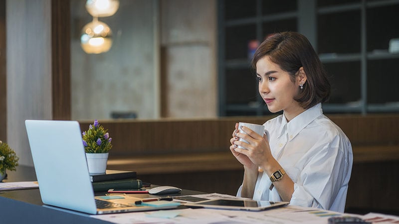 women holding to a mug infront of laptop