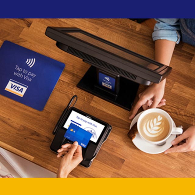 Image of an individual buying a coffee and paying using a Visa card for a cashless payment.